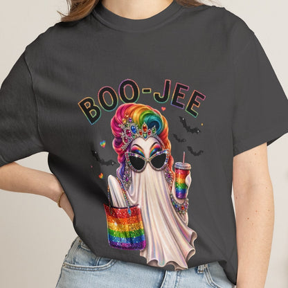 A lesbian wearing a dark charcoal gray graphic t-shirt with a colorful Halloween-themed design featuring a ghost, rainbow accents, and the text 'BOO-JEE', paired with light-wash denim shorts in a cozy indoor setting.