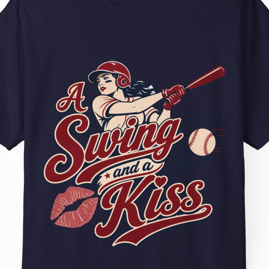 A navy blue short-sleeve t-shirt with a retro-style graphic on the front. The graphic features a pin-up illustration of a female baseball player swinging a bat, accompanied by the text 'A Swing and a Kiss' in red and white script, along with red lipstick marks and a baseball.