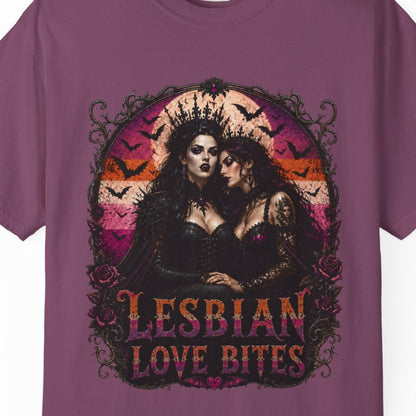 A purple short-sleeve crewneck t-shirt featuring a gothic graphic of two women embracing with the text 'LESBIAN LOVE BITES' in stylized lettering, displayed on a clean white background.
