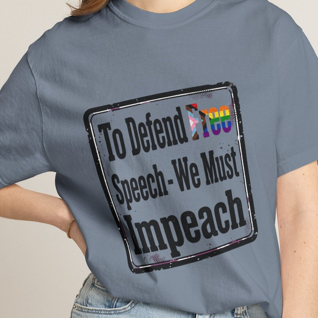 Lesbian wearing a blue short-sleeve t-shirt with a distressed rectangular graphic on the chest that reads 'To Defend Free Speech-We Must Impeach' in black text, featuring a small LGBTQ rainbow flag accent.