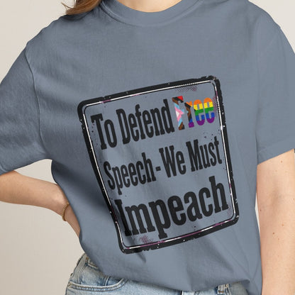 Lesbian wearing a blue short-sleeve t-shirt with a distressed rectangular graphic on the chest that reads 'To Defend Free Speech-We Must Impeach' in black text, featuring a small LGBTQ rainbow flag accent.
