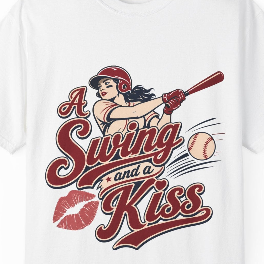 A white short-sleeve crewneck t-shirt featuring a retro-style graphic of a pin-up girl swinging a baseball bat with the text 'A Swing and a Kiss' and red lips.