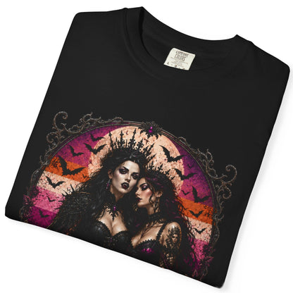 A folded black short-sleeve t-shirt with a gothic-style graphic print of two women, bats, and a pink and orange circular background, shown on a white background.