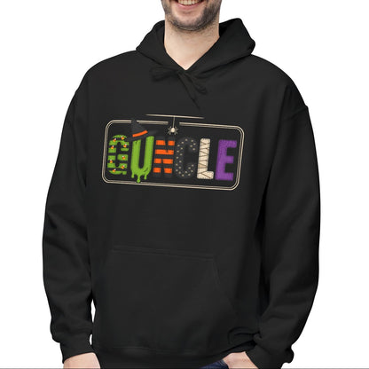 A gay man wearing a black pullover hoodie with a colorful retro-style 'GUNCLE' graphic on the chest, paired with blue jeans, set against a plain white background.