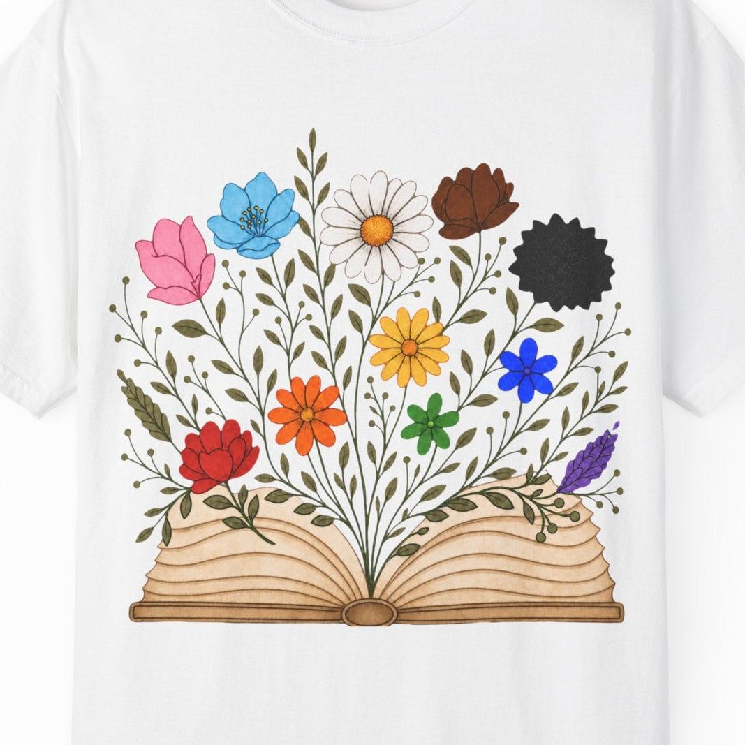 A white short-sleeve crewneck t-shirt featuring a colorful graphic of an open book with LGBTQ colored wildflowers blooming from the pages, displayed on a clean white background.