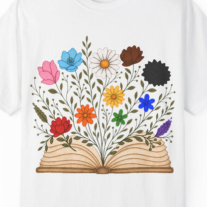 A white short-sleeve crewneck t-shirt featuring a colorful graphic of an open book with LGBTQ colored wildflowers blooming from the pages, displayed on a clean white background.