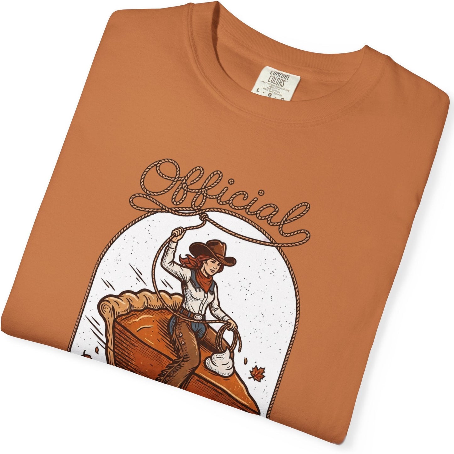 A folded orange crewneck t-shirt with a graphic print of a cowgirl riding a pie under the word 'Official' in script, displayed on a clean white background.