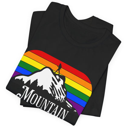 A mockup of a folded black Lesbian Pride tee that says Mountain Momma| LGBT Pride tee in rainbow background designed by Queer Energy 