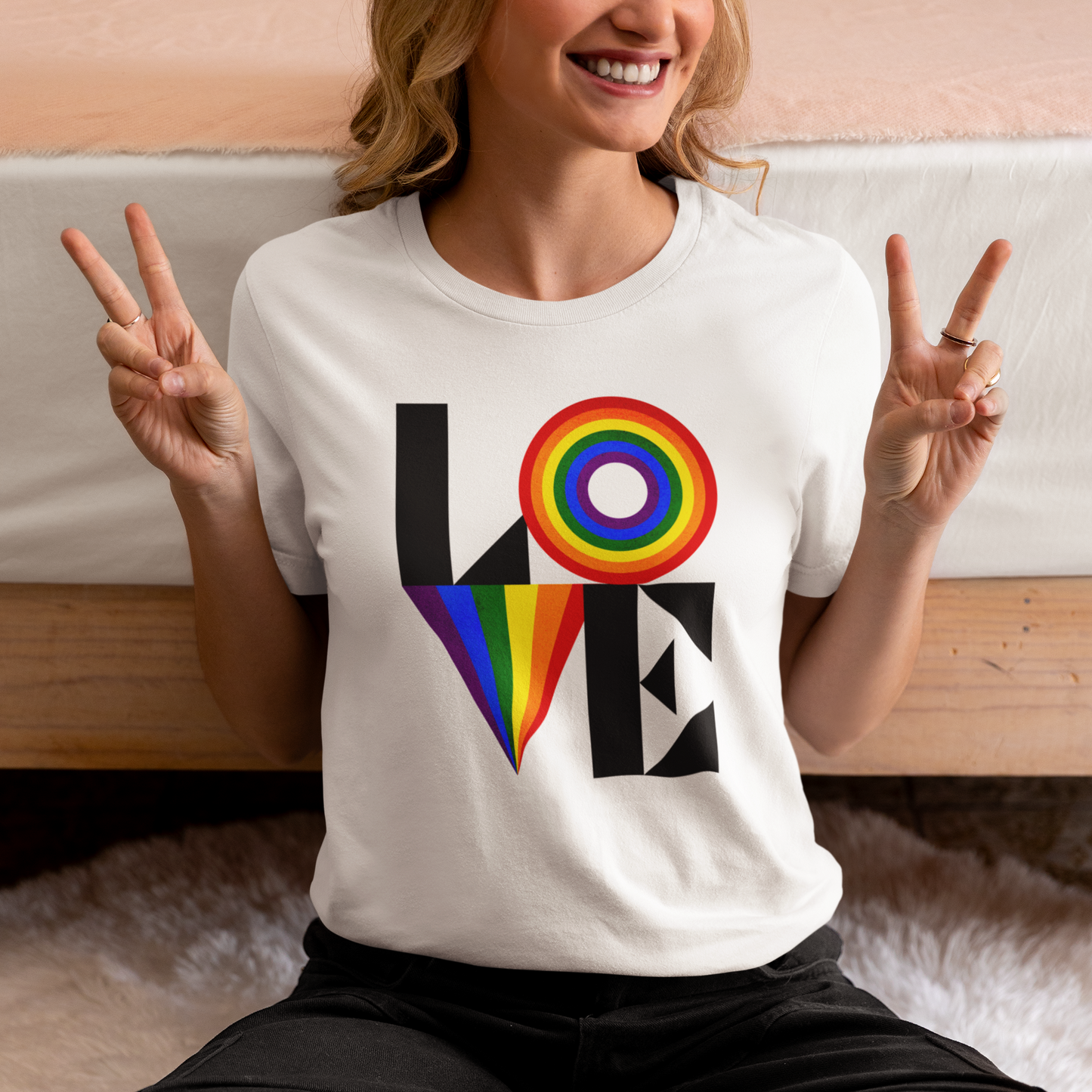 A mockup of a lesbian ear a white colored Gay Pride tee that says LOVE with LGBTQ rainbow colors | Pride t-shirt designed by Queer Energy 
