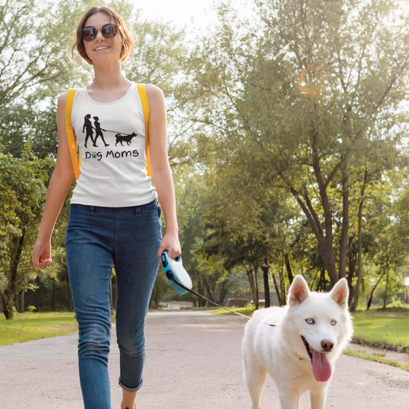 Lesbian wearing a racerback tank top that says "Dog Moms" while walking her dog