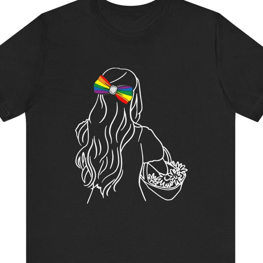 black Tee with the back of a long-haired lesbian wearing a rainbow bow tie in her hair, titled “Flower Girl” – Designed by Queer Energy