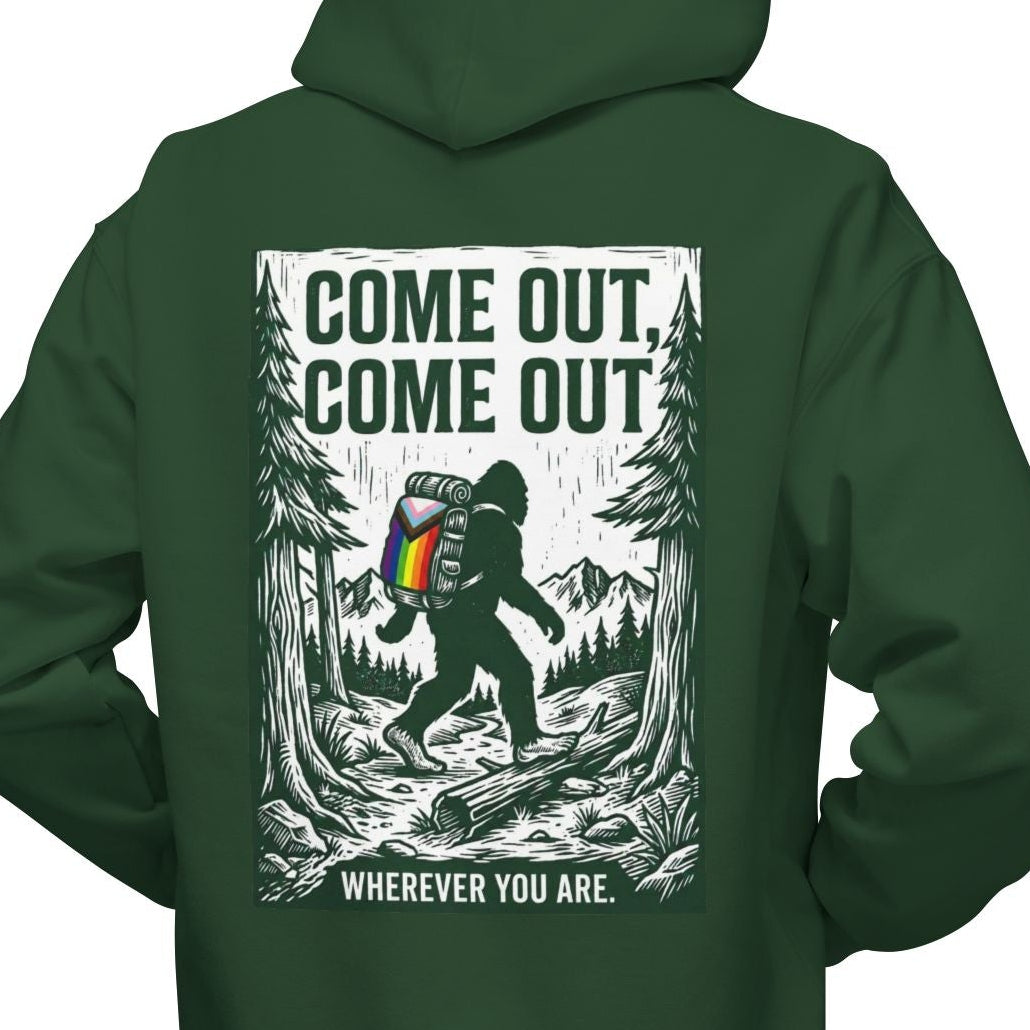 Gay man wearing a Gay pride green hoodie featuring Come Out, Come Out, Wherever You Are - Bigfoot design with Progress Pride backpack on the back by Queer Energy