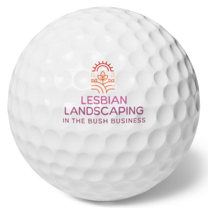 White golf ball that says: Lesbian Landscaping - In the bush business in Lesbian flag colors
