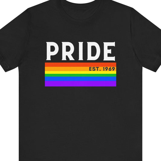 Black Tee that says “PRIDE EST. 1969” with a rainbow pride flag background – Designed by Queer Energy