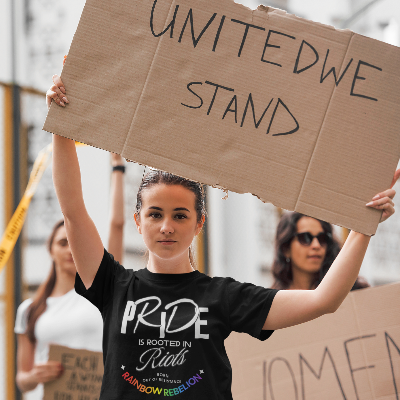mockup of lesbian wearing PRIDE IS ROOTED IN RIOTS – BORN OUT OF RESISTANCE – RAINBOW REBELLION | Pride Tee by Queer Energy